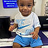 toddler, child, smiling, nike, white_tshirt, blue_shorts, store, counter, technology, electronics, indoor, person, portrait, cute, young_child, retail, shop, happy, casual_clothing, seated