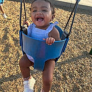 Milani joined the competition — help win amazing prizes! toddler, child, swing, playground, smiling, happy, outdoor, sunlight, woodchips, blue_swing, sneakers, clothing, person, joy, fun, summer, park, curly_hair, baby, feet