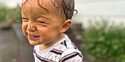 Gabriel is registered to the contest to win money with this photo: toddler, child, wet_hair, striped_shirt, smiling, outdoor, rainy_day, dirt, playful, happy, person, portrait, casual_clothing, messy, young_child, expression, standing, nature, daylight, fun