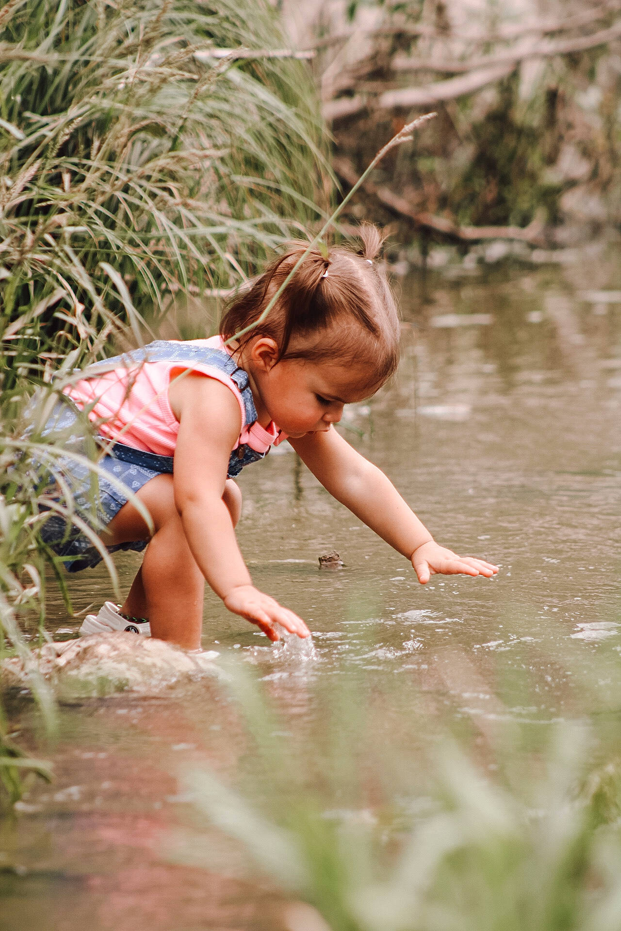 Lela is registered to the contest to win money with this photo: bank, blond, clothing, forest, fun, grass, hairstyle, happy, lake, leisure, people_in_nature, person, plant, recreation, shorts, stream, thigh, toddler, water, watercourse