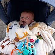 Mathis participe au concours pour gagner de l'argent avec cette photo : baby, blanket, stroller, toy, happy, smiling, child, infant, cozy, comfort, colorful, outdoor, hand, face, clothing, seat, play, cute, young, wrapped