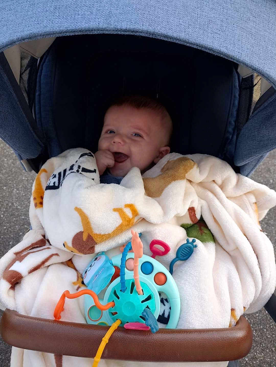Mathis participe au concours pour gagner de l'argent avec cette photo : baby, blanket, stroller, toy, happy, smiling, child, infant, cozy, comfort, colorful, outdoor, hand, face, clothing, seat, play, cute, young, wrapped