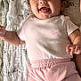 baby, child, smiling, tongue_out, pink_clothing, headband, shorts, blanket, zebra_pattern, cute, happy, infant, laying_down, indoor, soft_light, portrait, face, cheerful, person, young_child