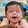 Emily is registered to the contest to win money with this photo: baby, child, face, smiling, happy, outdoor, water_bottle, snack_bag, table, person, skin, hair, hand, summer, daylight, cute, closeup, holding, infant, expression