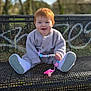 baby, toddler, red_hair, smiling, bench, park, outdoors, grass, trees, sweater, shoes, pacifier, toy, pacifier_clip, sitting, portrait, bokeh, sunlight, cute, happy