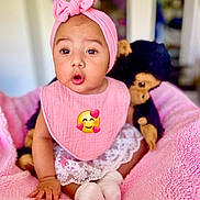 Gio is registered to the contest to win money with this photo: adorable, baby, child, clothing, cute, expression, home, indoor, infant, monkey_toy, pink_bib, pink_blanket, pink_headband, plush_toy, portrait, seated, socks, soft_texture, wide_eyes, young_child