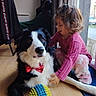 affection, animal, black_and_white, bow_tie, carpet, child, curtain, cute, dog, floor, flooring, home, indoor, natural_light, pajamas, pet, playing, toy, window, young_child