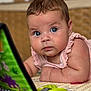 baby, blue_eyes, curious, play_mat, toy_book, indoor, close_up, infant, child, colorful, soft_lighting, face, skin, arm, clothing, pink_outfit, expression, young_child, focus, floor