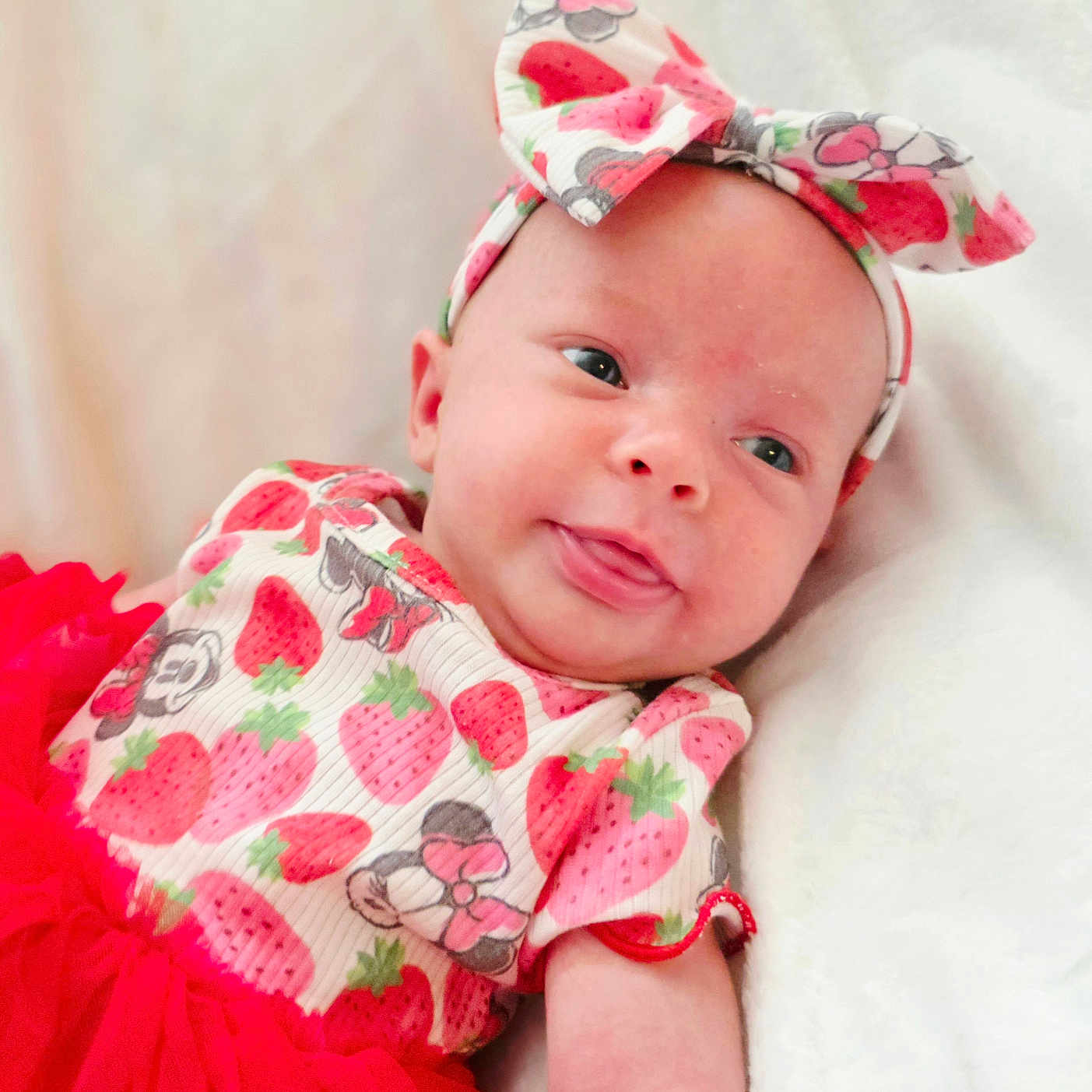 Zela Leitschuck is registered to the contest to win money with this photo: baby, baby_girl, bow, child, closeup, clothing, cute, face, happy, headband, infant, lying_down, person, portrait, red_dress, skin, smiling, soft_background, strawberry, tongue_out