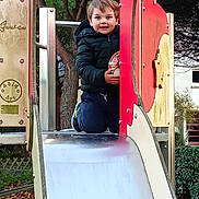 Milan participe au concours pour gagner de l'argent avec cette photo : child, playground, slide, ball, smiling, outdoor, tree, jacket, happy, play, park, boy, casual_clothing, daylight, recreation, fun, toy, nature, kneeling, sport_shoes