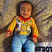 Gianni joined the competition — help win amazing prizes! baby, child, smile, face, cowboy, outfit, blanket, blue_pants, red_cuffs, indoor, cute, happy, infant, person, clothing, texture, warm, playful, portrait, lying_down