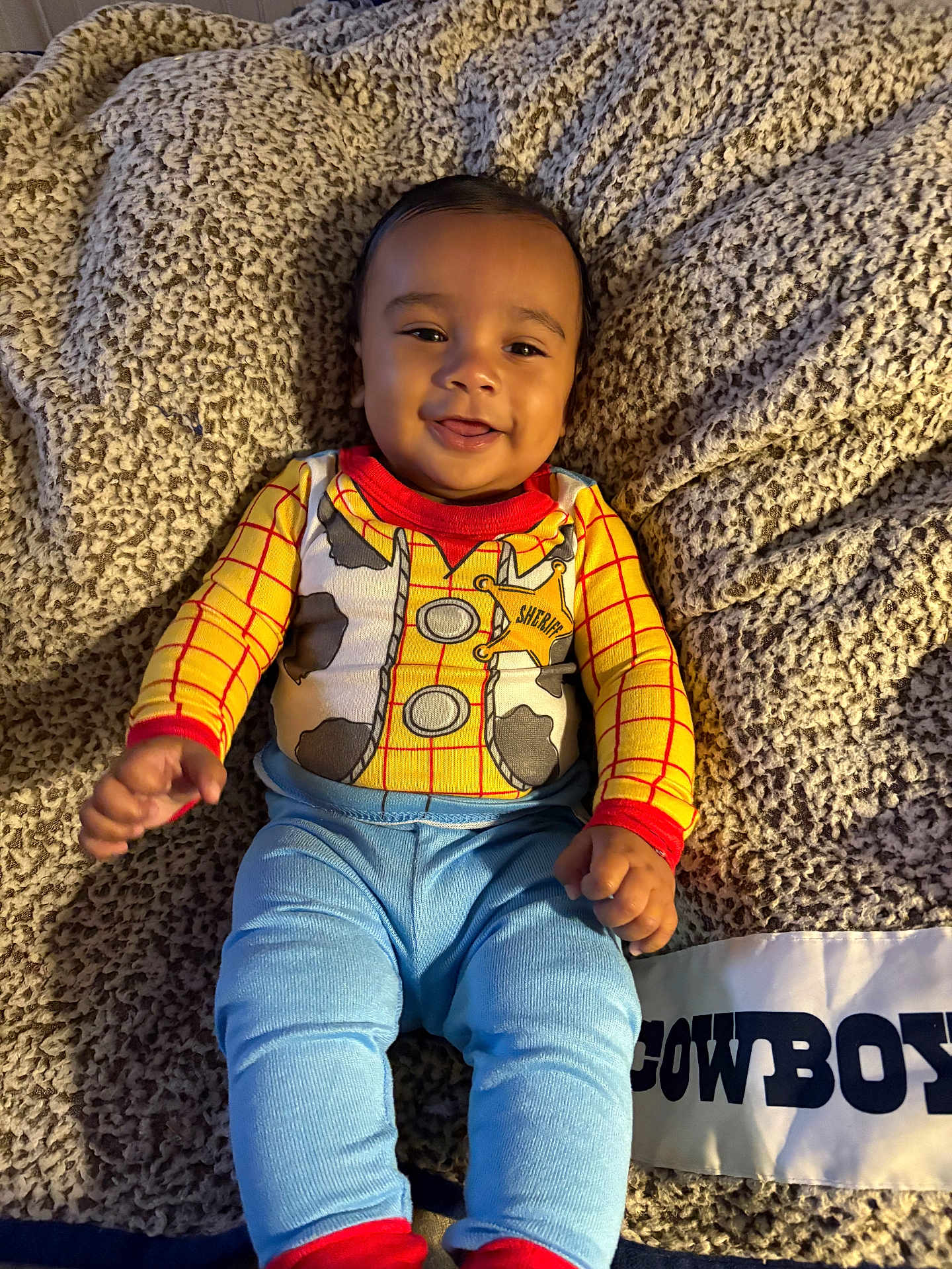 Gianni joined the competition — help win amazing prizes! baby, child, smile, face, cowboy, outfit, blanket, blue_pants, red_cuffs, indoor, cute, happy, infant, person, clothing, texture, warm, playful, portrait, lying_down