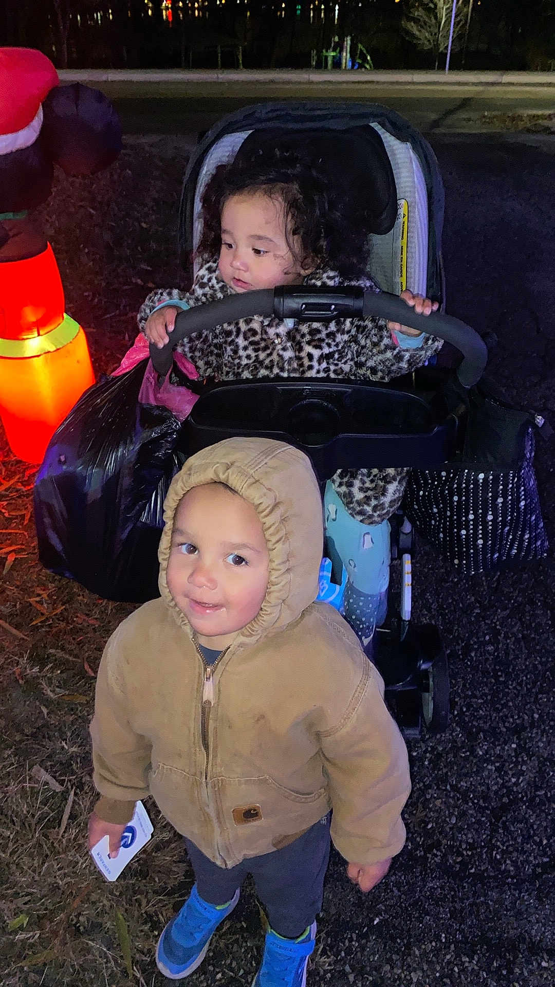 Luciousrowan is registered to the contest to win money with this photo: child, toddler, stroller, hooded_jacket, leopard_print, toy, outdoor, night, inflatable_decoration, shoes, card, curly_hair, grass, pavement, winter_clothing, cute, smile, playful, family, festive