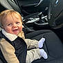 baby, child, smile, car_interior, seat, clothing, vest, beige, black, sock, happy, person, portrait, steering_wheel, bmw_logo, car_seat, window, door, gear_shift, casual