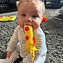 Arthur is registered to the contest to win money with this photo: baby, blurred_background, carpet, chewing, child, colorful_toys, cute, face, floor, hand, home, indoor, infant, orange_spots, playtime, sitting, soft_lighting, striped_pajamas, toy, yellow_toy