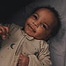 Kamari is registered to the contest to win money with this photo: baby, infant, smile, face, pajamas, moon, stars, sleepwear, curly_hair, lying_down, bed, blanket, child, cute, portrait, indoors, soft_lighting, happy, cozy, person