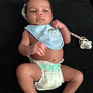 Kamari joined the competition — help win amazing prizes! baby, infant, diaper, bib, pacifier, clothing, skin, face, hand, foot, lying_down, black_background, cute, child, newborn, expression, indoors, person, young, resting