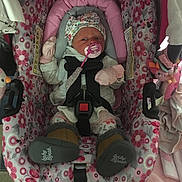 Chloe is registered to the contest to win money with this photo: baby, car_seat, pacifier, mittens, hat, blanket, toy, infant, child, clothing, pink, floral_pattern, seatbelt, indoor, person, cute, sleepwear, soft_toys, comfort, newborn