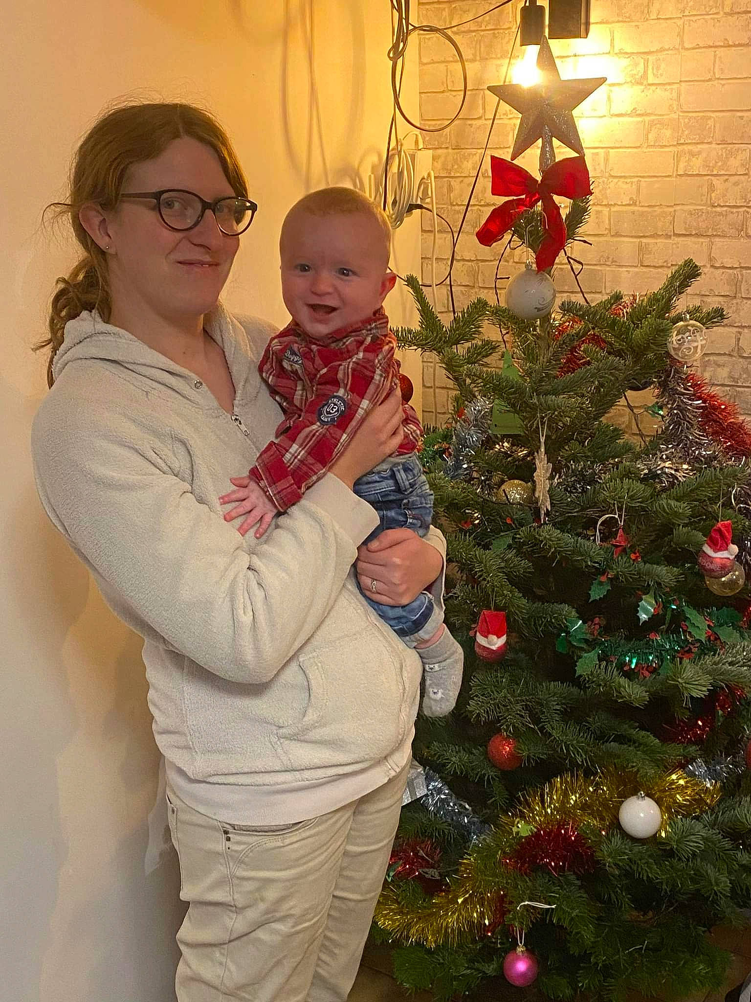 Robin a rejoint le concours — aidez-le/la à gagner de superbes lots ! christmas_decoration, christmas_ornament, christmas_tree, event, evergreen, facial_expression, glasses, happy, head, holiday_ornament, human_body, joy, lighting, ornament, person, sleeve, smile, standing, toddler, tree