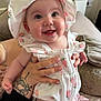 baby, child, clothing, couch, cute, eyes, face, hand, happy, hat, indoors, infant, nail_polish, person, pillow, skin, smiling, strawberry_pattern, tattoo, tongue