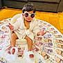 Trisha joined the competition — help win amazing prizes! baby, child, sunglasses, robe, money, british_pounds, floor, chair, wooden_floor, currency, indoor, plush, footwear, expression, sitting, cute, fashion, accessory, luxury, portrait