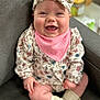 Brynley is registered to the contest to win money with this photo: baby, smiling, headband, floral_pattern, pink_bib, sitting, gray_chair, cute, happy, infant, indoors, soft_lighting, child, sock, clothing, portrait, person, baby_outfit, comfortable, closeup