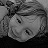 black_and_white, blanket, casual, child, close_up, cozy, cute, face, hair, happy, indoors, lying_down, pattern, portrait, relaxed, resting, smiling, soft_texture, warm, young