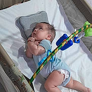 Liam joined the competition — help win amazing prizes! baby, infant, playpen, onesie, toy, pillow, floor, looking_up, curious, child, diaper, blanket, mesh_sides, colorful, animal_print, indoor, cute, lying_down, soft, playtime