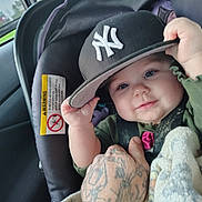 Starla joined the competition — help win amazing prizes! baby, infant, car_seat, hat, cap, new_york_yankees, hand, tattoo, blanket, smile, face, eyes, clothing, car_interior, seatbelt, child, person, holding, cute, portrait