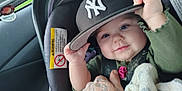 Starla joined the competition — help win amazing prizes! baby, infant, car_seat, hat, cap, new_york_yankees, hand, tattoo, blanket, smile, face, eyes, clothing, car_interior, seatbelt, child, person, holding, cute, portrait