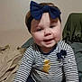 baby, child, headband, bow, striped_shirt, golden_bear, smiling, face, indoor, bed, blanket, clothing, seated, cute, young_child, portrait, happy, person, casual, infant