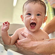 Mattéo participe au concours pour gagner de l'argent avec cette photo : baby, infant, bathtub, bath, water, hand, adult_hand, smile, open_mouth, eyes, wet_hair, cheeks, skin, indoor, portrait, closeup, happy, playful, parental_care, supporting_hand