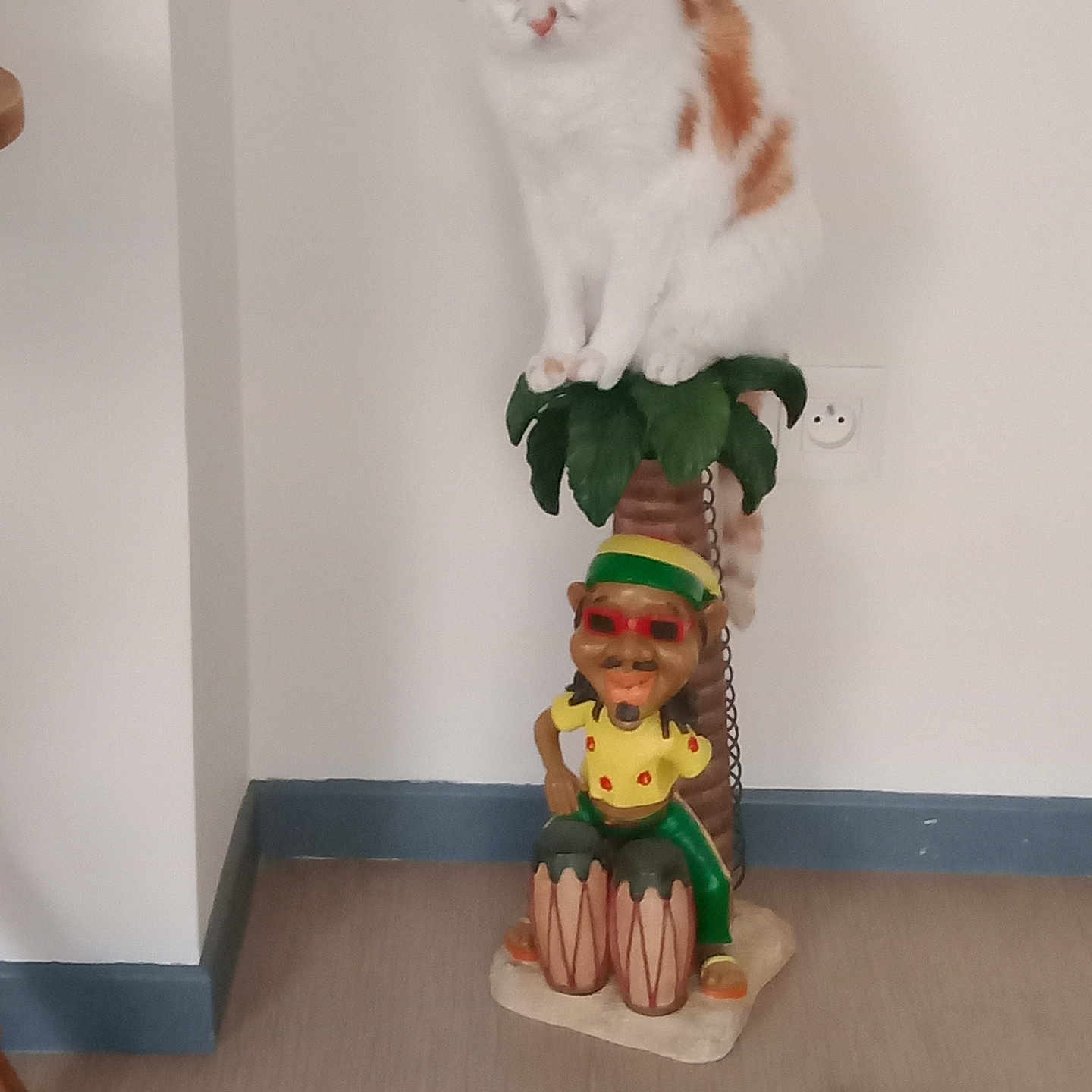 Véra participe au concours pour gagner de l'argent avec cette photo : cat, statue, indoor, white_wall, floor, toy_ball, orange_cat, decor, perched, animal, curious, plant_statue, drums, colorful, figure, home_interior, pet, playful, feline, object
