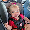 baby, child, car_seat, smiling, pink_bow, red_clothing, seatbelt, happy, infant, car_interior, safety, cute, face, portrait, young_child, straps, sitting, hands, closeup, joyful