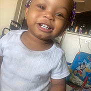 Truee is registered to the contest to win money with this photo: child, toddler, smiling, indoor, white_shirt, beads, hair_accessory, mickey_mouse, chair, furniture, happy, person, face, home, toy, colorful, cute, young_child, casual, portrait