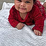 Alani is registered to the contest to win money with this photo: baby, baby_girl, blanket, child, closeup, curly_hair, cute, face, hands, happy, infant, lying_down, outdoor, portrait, red_clothing, smile, texture, toddler, warm_clothing, white_bow