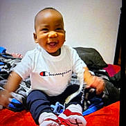 Zyaire joined the competition — help win amazing prizes! baby, child, smiling, tshirt, clothing, sitting, blanket, red, blue, black, white, face, happy, indoor, person, footwear, pants, toy, bed, casual