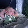 baby, sleeping, infant, cushion, elephant_print, pillow, blanket, green_clothing, white_clothing, peaceful, indoor, resting, newborn, face, head, arm, soft_light, cozy, child, portrait