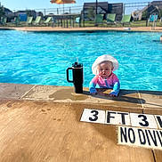 Emily Sophia is registered to the contest to win money with this photo: baby, child, pool, water, swimming_pool, toddler, hat, hoodie, sun_hat, tumbler, drink, outdoor, daylight, blue, relaxation, summer, fence, umbrella, lawn_chair, concrete