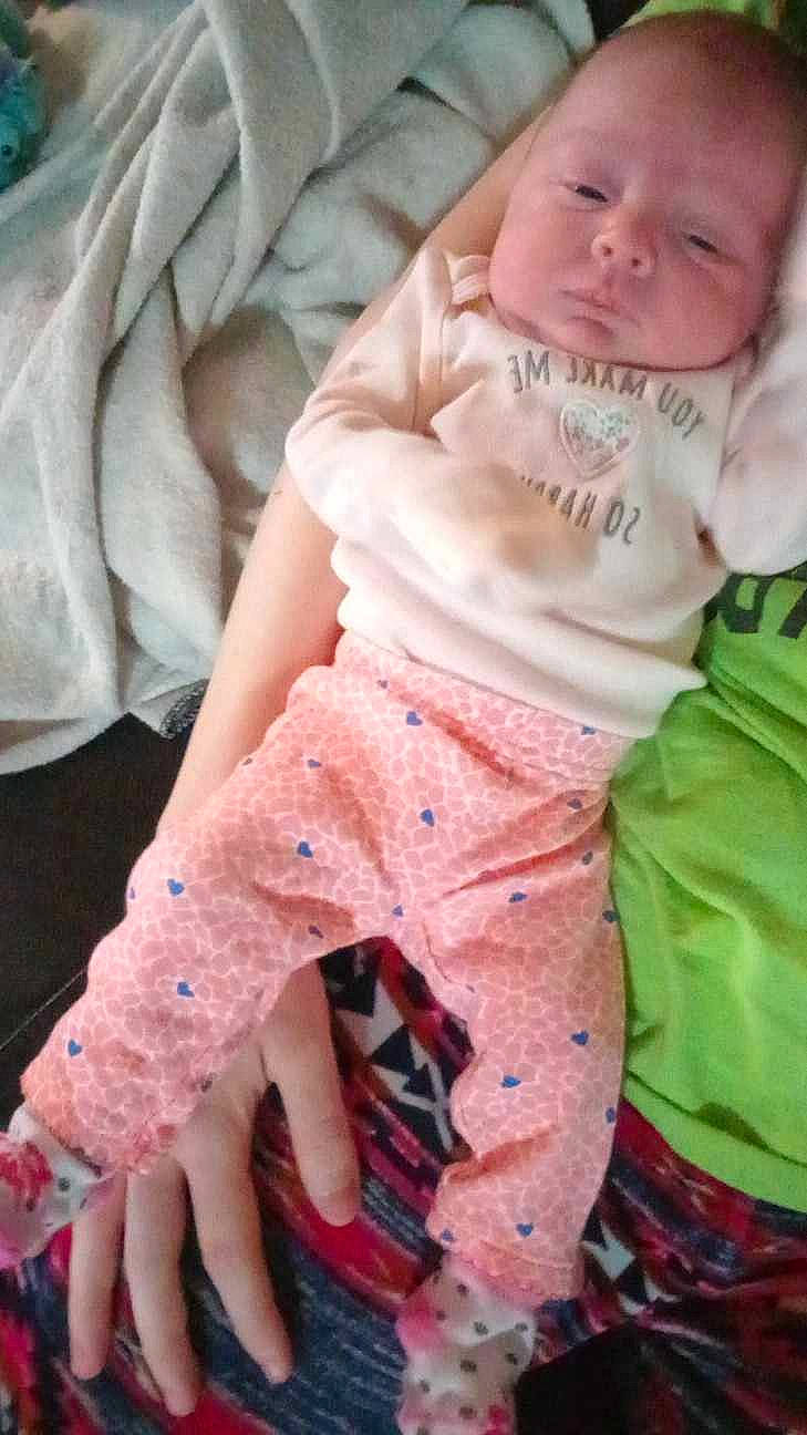 Jessica is registered to the contest to win money with this photo: baby, baby_toddler_clothing, cheek, child, comfort, finger, gesture, happy, leg, linens, magenta, pattern, person, pink, sitting, skin, sleeve, textile, thigh, thumb