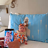 Sosie joined the competition — help win amazing prizes! baby, infant, smiling, bed, pillow, hand, smartphone, clothing, headband, person, indoor, face, happy, fabric, colorful, photography, cute, child, sitting, skin