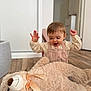 toddler, child, baby, toy, teddy_bear, stuffed_animal, floor, wooden_floor, indoors, home, romper, corduroy, happy, smiling, raising_hands, cute, plush, ribbon, person, cozy