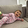Alba participe au concours pour gagner de l'argent avec cette photo : baby, child, smiling, striped_onesie, couch, living_room, toy, happy, infant, face, person, indoor, cozy, furniture, sitting, cute, playful, comfort, portrait, cushion