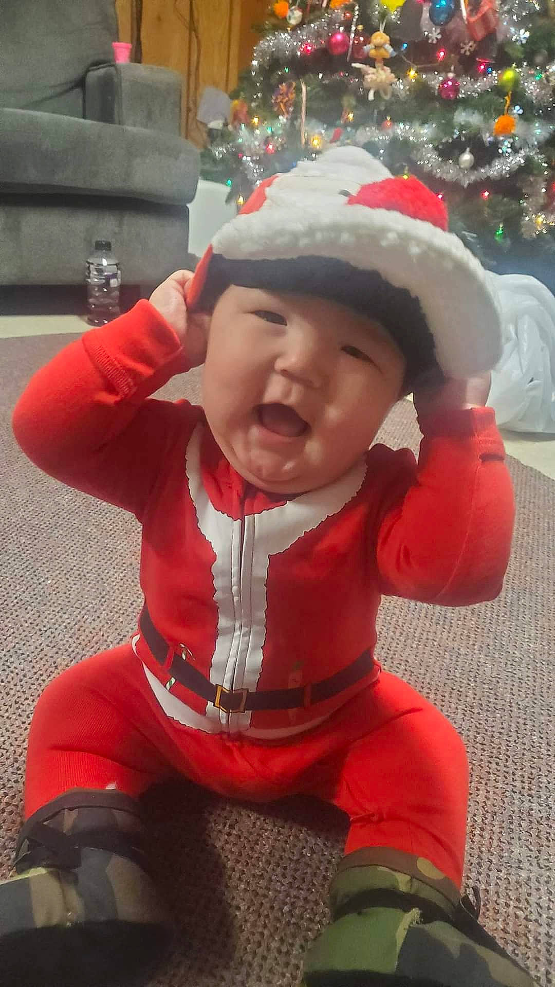Peter is registered to the contest to win money with this photo: baby, baby_toddler_clothing, cheek, child, christmas, christmas_tree, event, fun, happy, head, headwear, holiday, human_body, person, personal_protective_equipment, red, skin, sleeve, standing, toddler