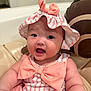 baby, child, infant, pink, hat, bow, smile, cute, face, chubby_cheeks, striped_clothing, sitting, indoors, seat, cushion, portrait, happy, headwear, person, closeup