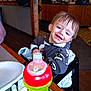Charles joined the competition — help win amazing prizes! toddler, child, smile, high_chair, sippy_cup, table, restaurant, wooden_decor, face, messy_face, clothing, indoor, happy, person, drinkware, plate, napkin, floor, seat, baby