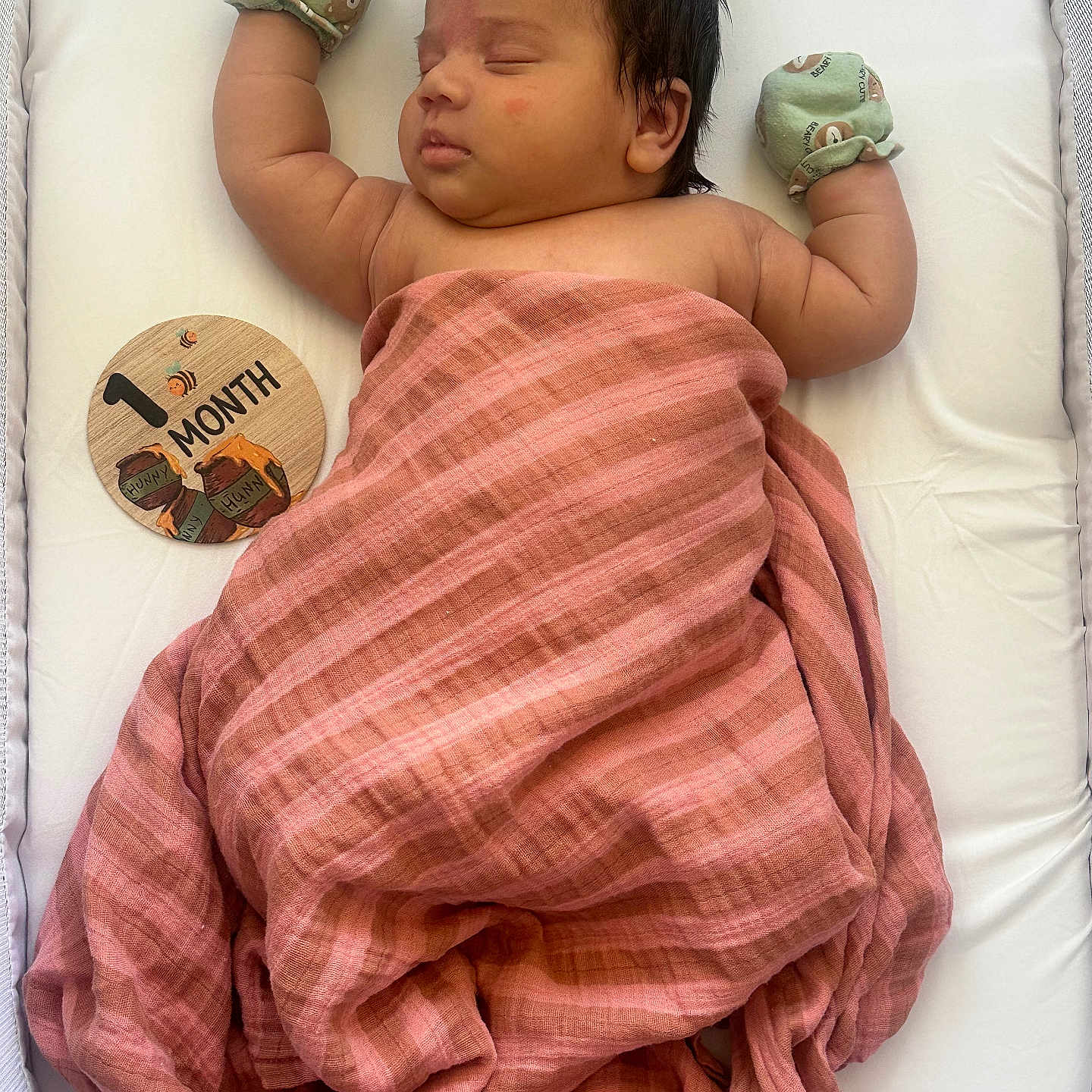 Cassian is registered to the contest to win money with this photo: baby, sleeping, blanket, mittens, milestone, wooden_plaque, infant, cute, cozy, pink, striped, face, person, resting, soft_lighting, portrait, newborn, lying_down, white_background, peaceful