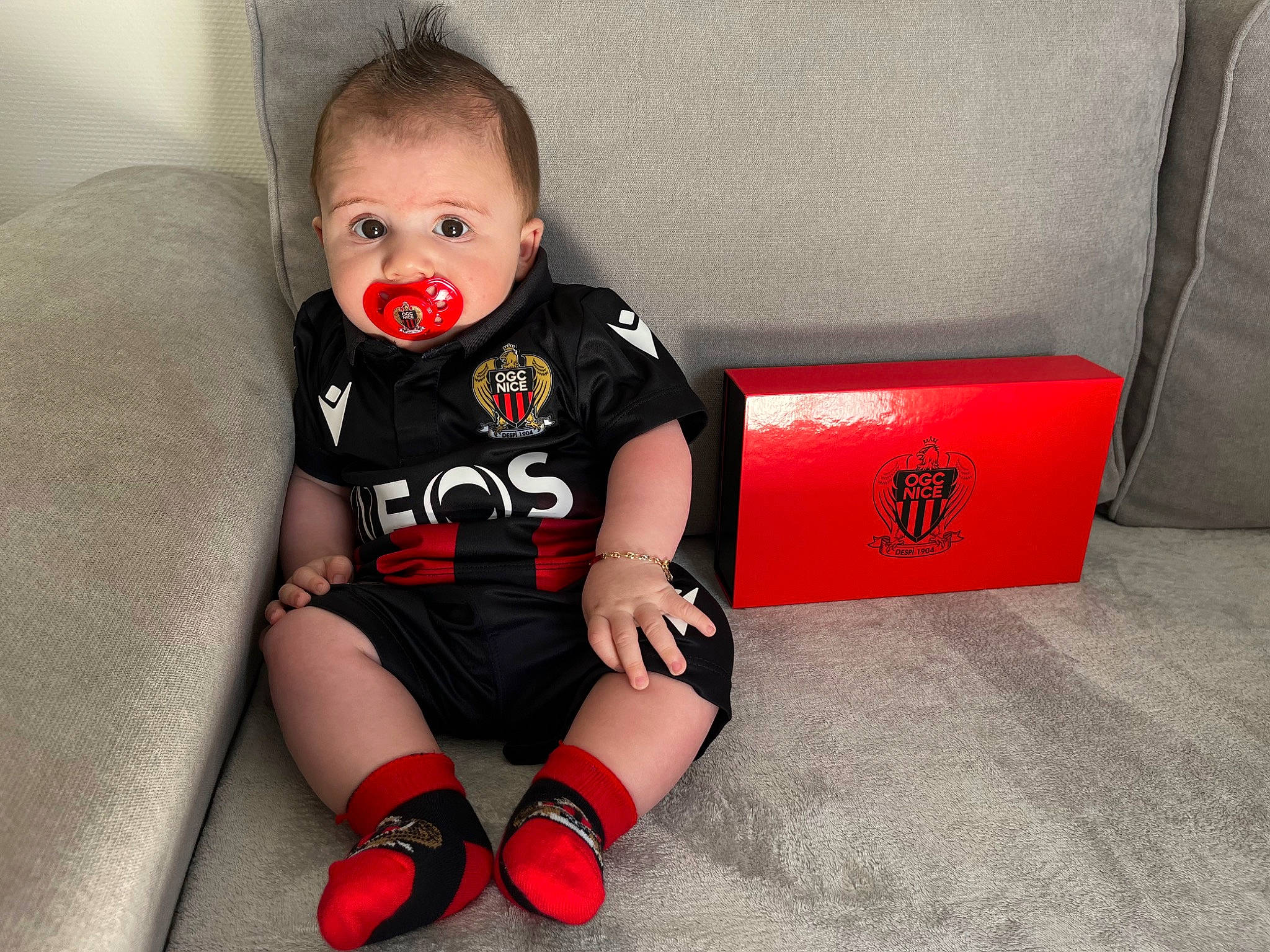 Eden a rejoint le concours — aidez-le/la à gagner de superbes lots ! baby, baby_toddler_clothing, box, carmine, child, comfort, facial_expression, flash_photography, flooring, fun, happy, human_body, human_leg, knee, pattern, person, sitting, sleeve, t_shirt, thigh