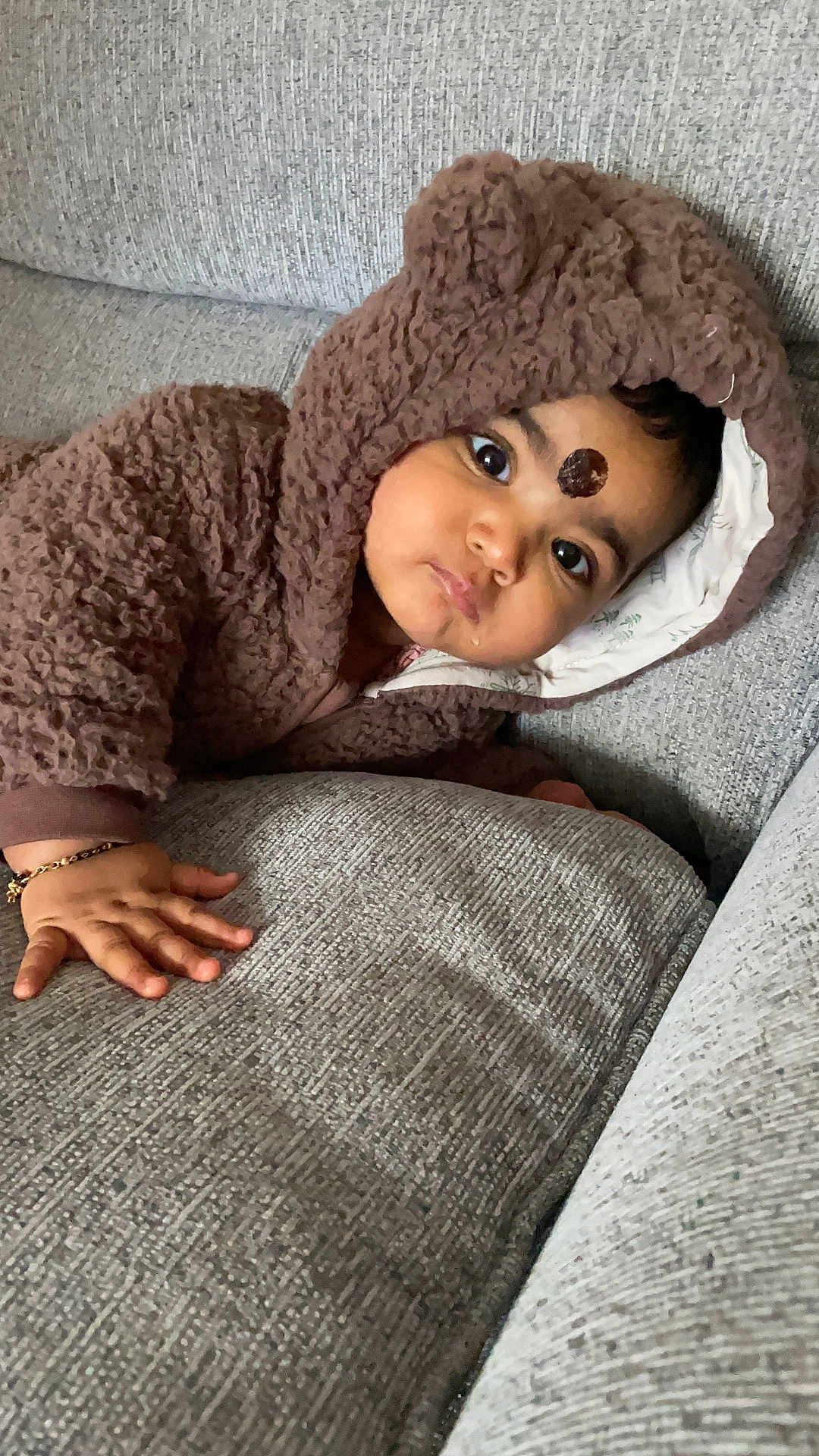 Merxin joined the competition — help win amazing prizes! baby, child, hoodie, brown_clothing, couch, sofa, hand, face, curious, indoors, texture, fuzzy, cute, portrait, young_child, infant, comfortable, cozy, expression, casual