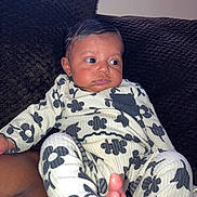 Wynter joined the competition — help win amazing prizes! baby, infant, child, clothing, onesie, floral_pattern, foot, hand, face, skin, texture, couch, blanket, indoors, portrait, cute, relaxed, expression, person, sitting